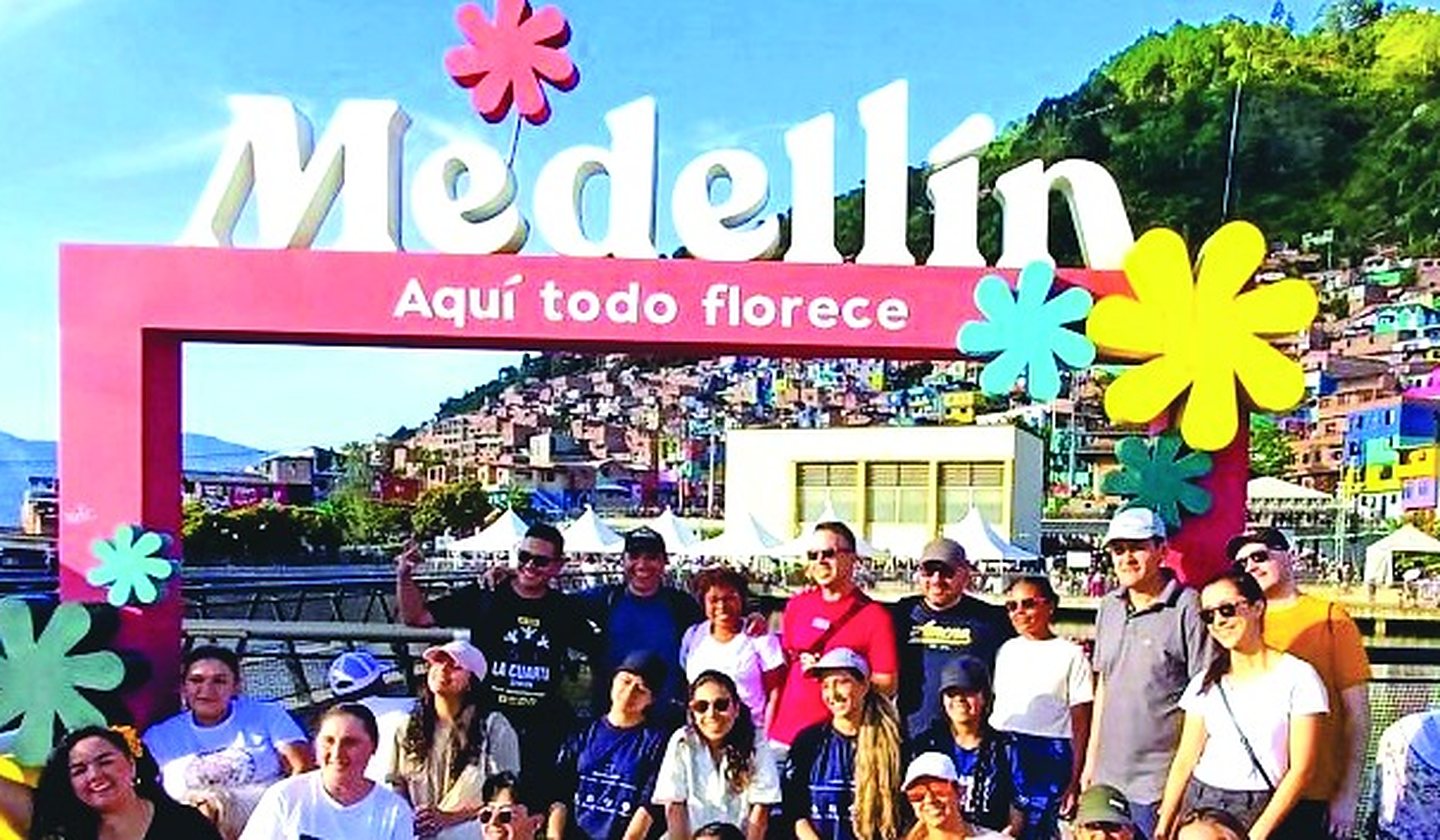 A tour group under the Medellín “aquí todo florece” sign