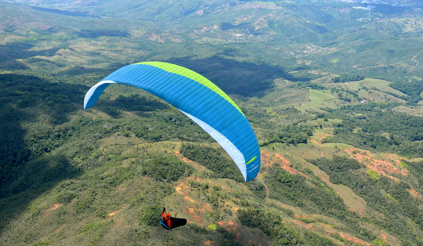 A paraglider over green valleys